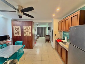 A modern kitchen with wooden cabinets, a stainless steel refrigerator, and a dining area with a table and chairs. - Soundproof apartment on the boardwalk with a balcony (half a block from the beach) (Puerto Vallarta)