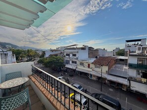A balcony with a view of a street, buildings, and a clear sky. - Soundproof apartment on the boardwalk with a balcony (half a block from the beach) (Puerto Vallarta)