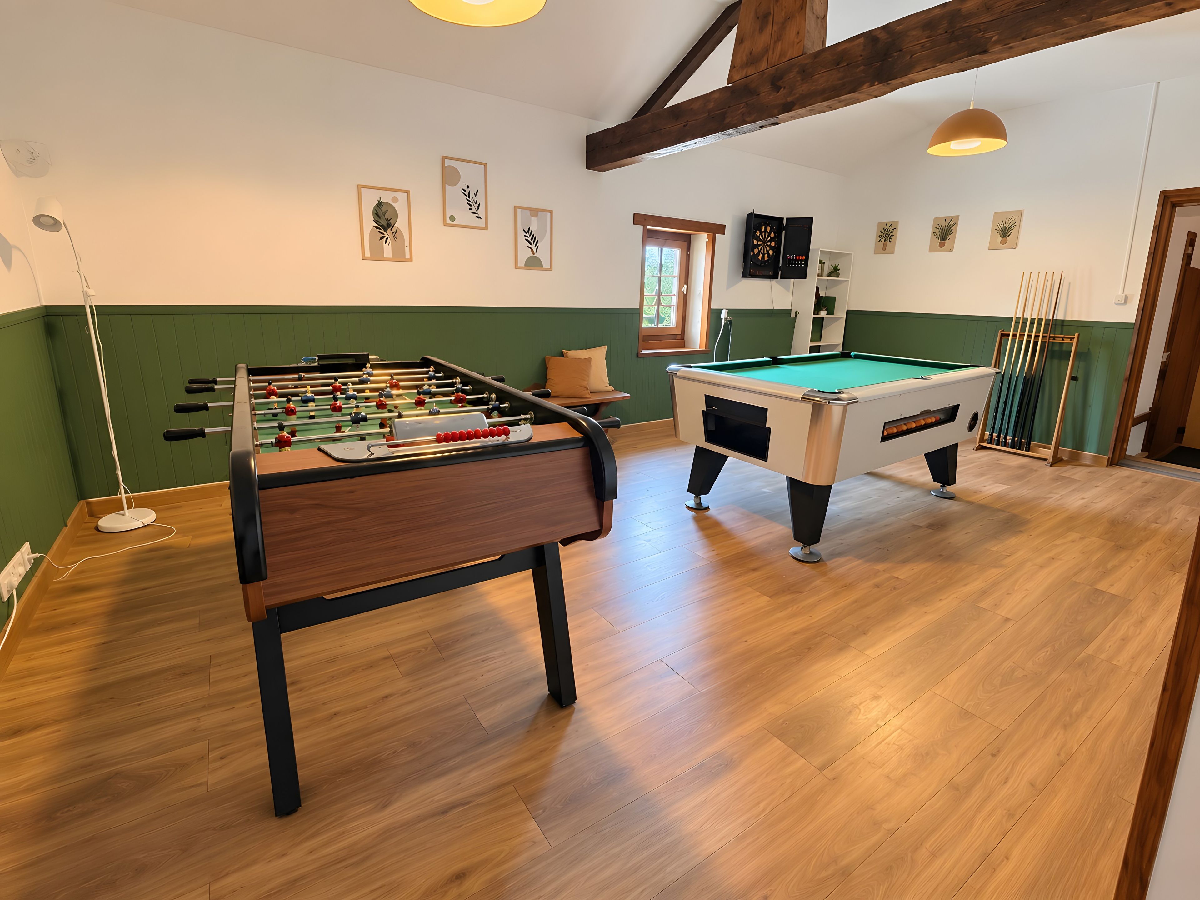Une pièce équipée d’un baby-foot, d’une table de billard et d’un jeu de fléchettes.