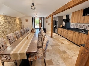 Een moderne keuken met houten kastjes en een lange eettafel.