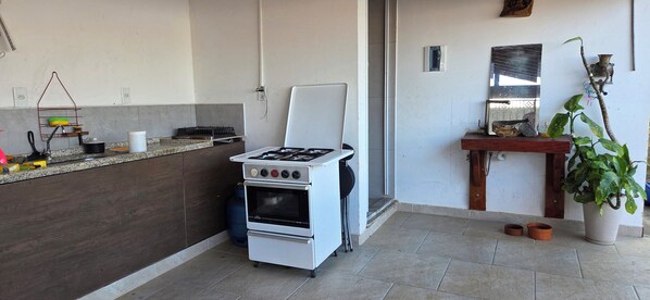 A compact kitchen with a gas stove, oven, and a small countertop. - Vrbo Property (Vila Nery)