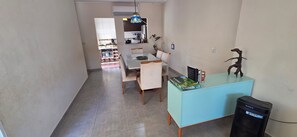 A dining area with a table and chairs, a blue cabinet with a Scrabble box, and a Sony trash bin. - Vrbo Property (Vila Nery)