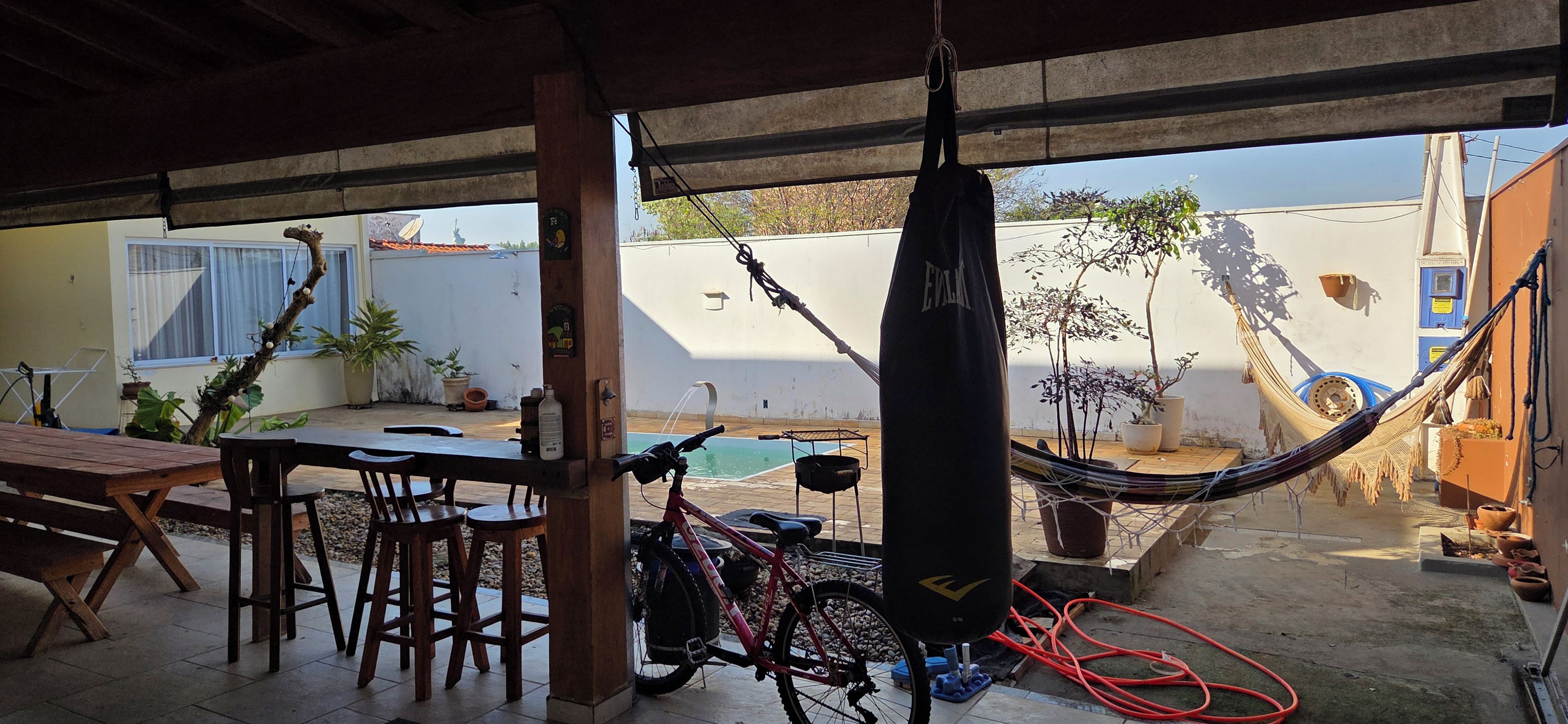 Un patio con mesa y sillas, una hamaca, una bicicleta y una piscina.