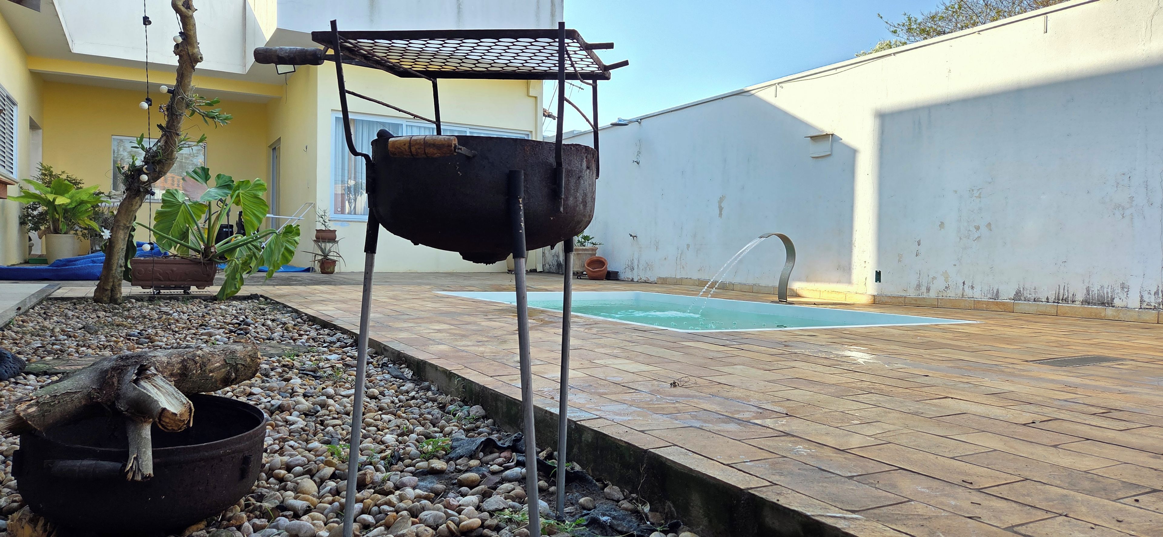 En trädgård med en grill, en swimmingpool och krukväxter.