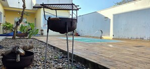 A backyard with a barbecue grill, a swimming pool, and potted plants. - Vrbo Property (Vila Nery)