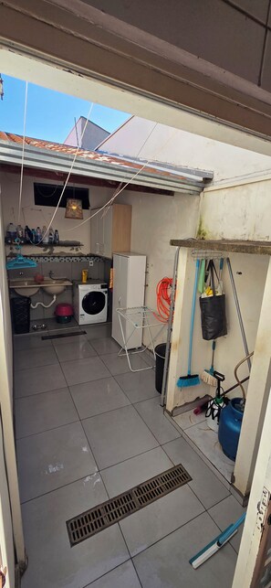 A compact kitchen with a washing machine, sink, and a drying rack.
