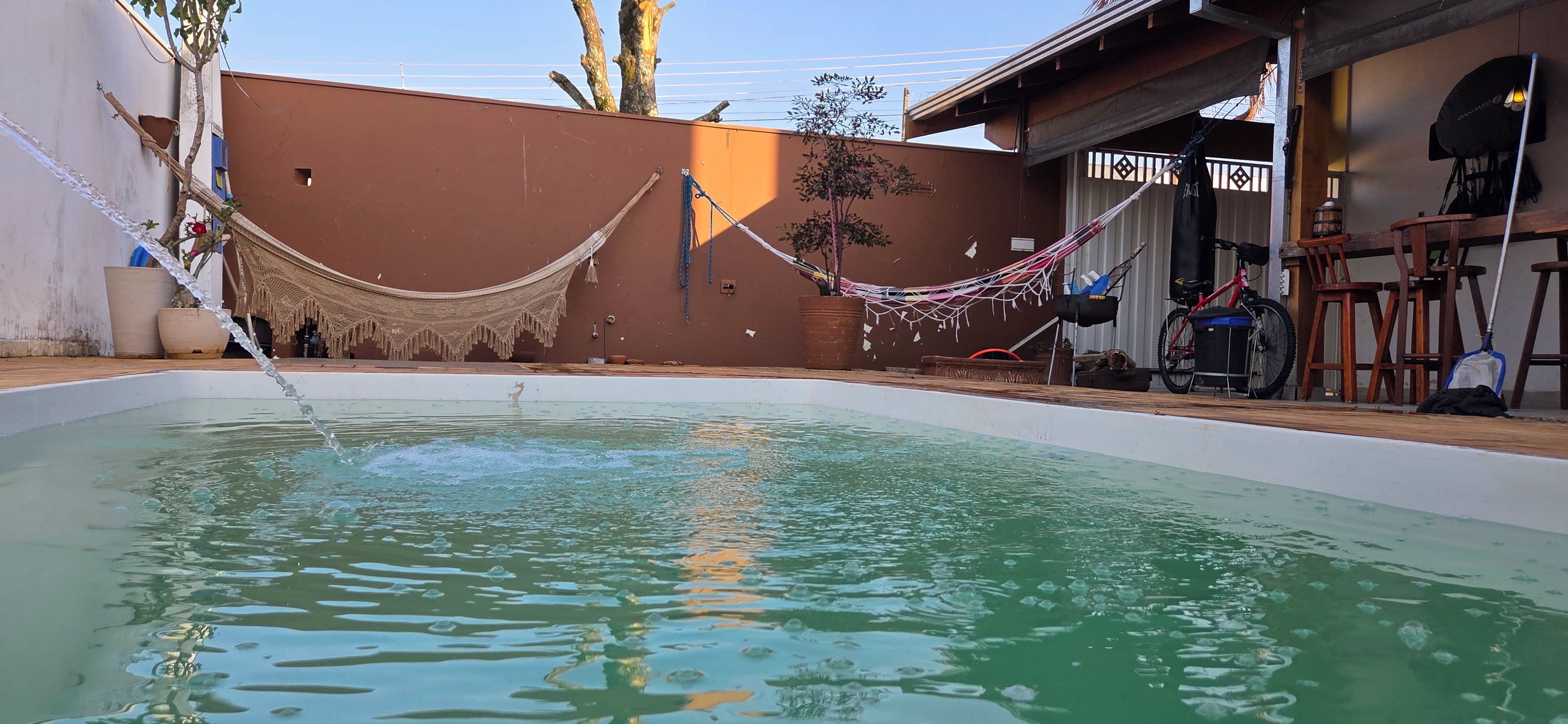 A swimming pool with a hammock and a bicycle in the background.