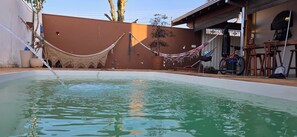 A swimming pool with a hammock and a bicycle in the background. - Vrbo Property (Vila Nery)