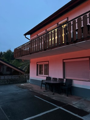 Een gebouw met twee verdiepingen, een balkon, terrasplek en een garage.