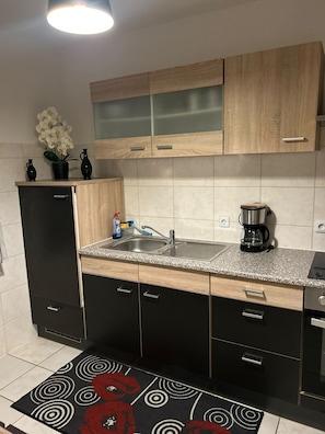 Een moderne keuken met een gootsteen, kasten, een koffiezetapparaat en een decoratieve plant.