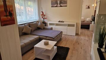 A modern living room with a sofa, a coffee table, and a white TV stand.