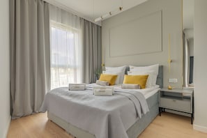 A modern bedroom with a bed, bedside tables, and a mirror. - Kapitanat Riverside by Downtown Apartments (Gdańsk)
