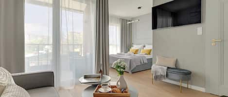 Habitació d'hotel moderna amb llit, zona de seients i televisió penjada a la paret.