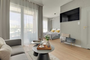 A modern hotel room with a bed, seating area, and a TV mounted on the wall. - Kapitanat Riverside by Downtown Apartments (Gdańsk)