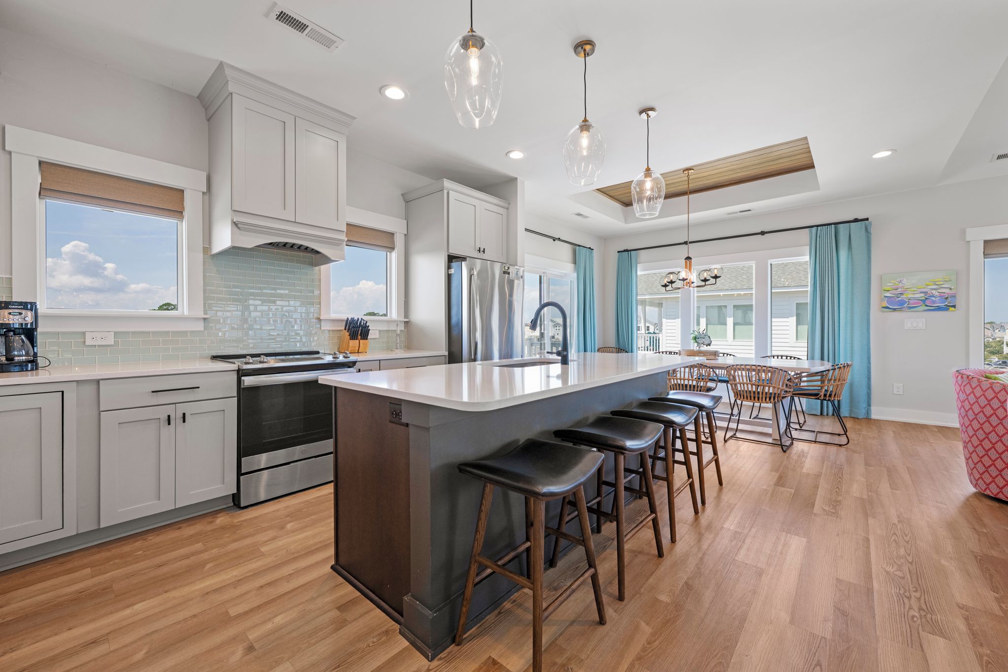 A modern kitchen with a central island, stainless steel appliances, and a dining area with bar stools.
