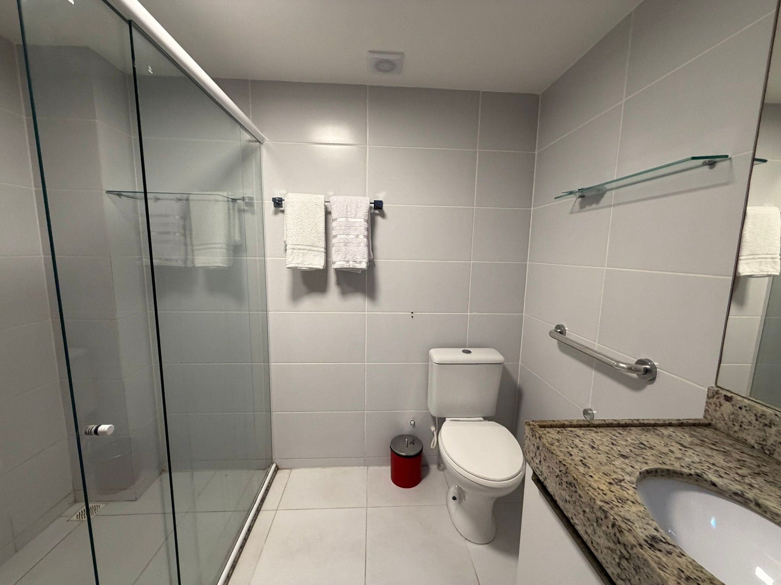 Un baño moderno con cabina de ducha de vidrio, inodoro y lavabo de granito.