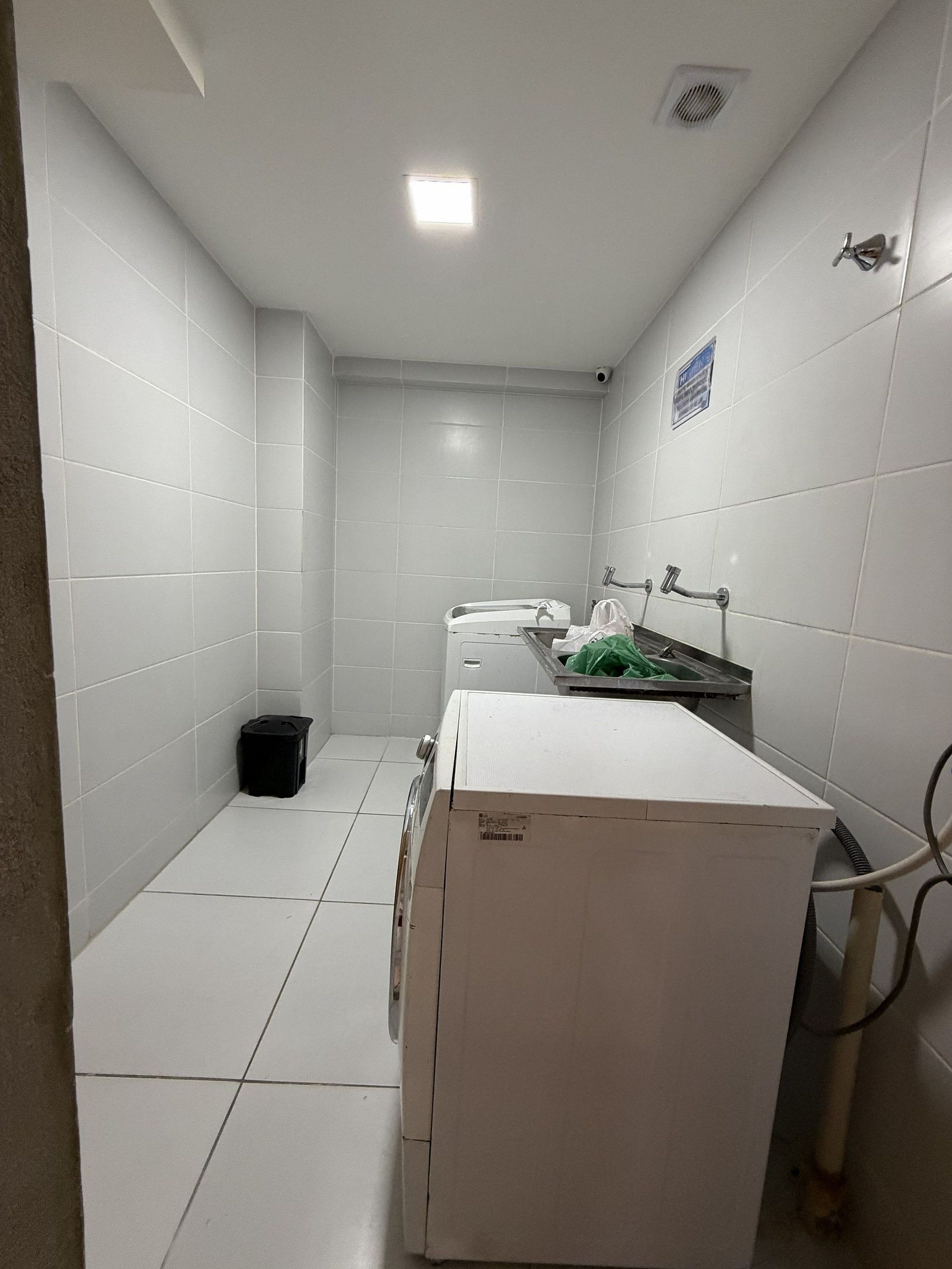 Ein kleines, sauberes Badezimmer mit weißen Fliesen, einer Toilette, einem Waschbecken und einem Mülleimer.