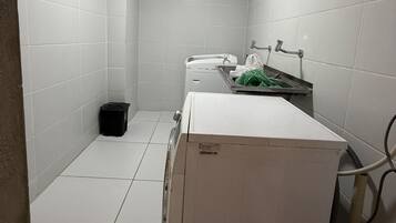 Ein kleines, sauberes Badezimmer mit weißen Fliesen, einer Toilette, einem Waschbecken und einem Mülleimer.