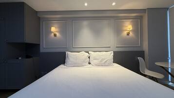 Une chambre d’hôtel avec un grand lit, deux lampes de chevet, un bureau et une chaise.