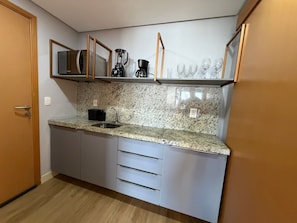 A compact kitchen with a granite countertop, a built-in coffee maker, and a microwave. - Manaíra Apart Hotel  (João Pessoa)