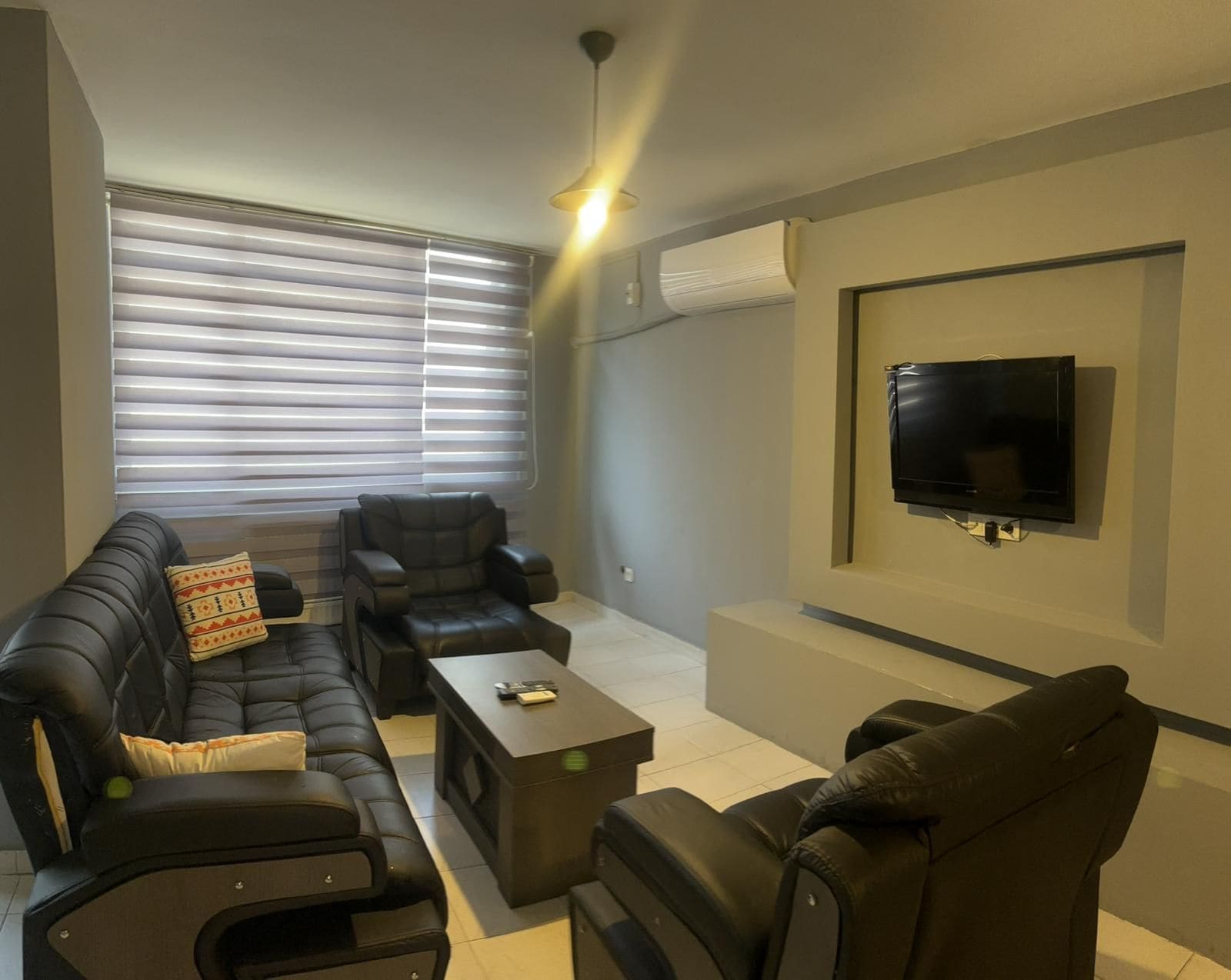 Una sala de estar moderna con un conjunto de sofá, una mesa de centro y un televisor de pantalla plana montado en la pared.