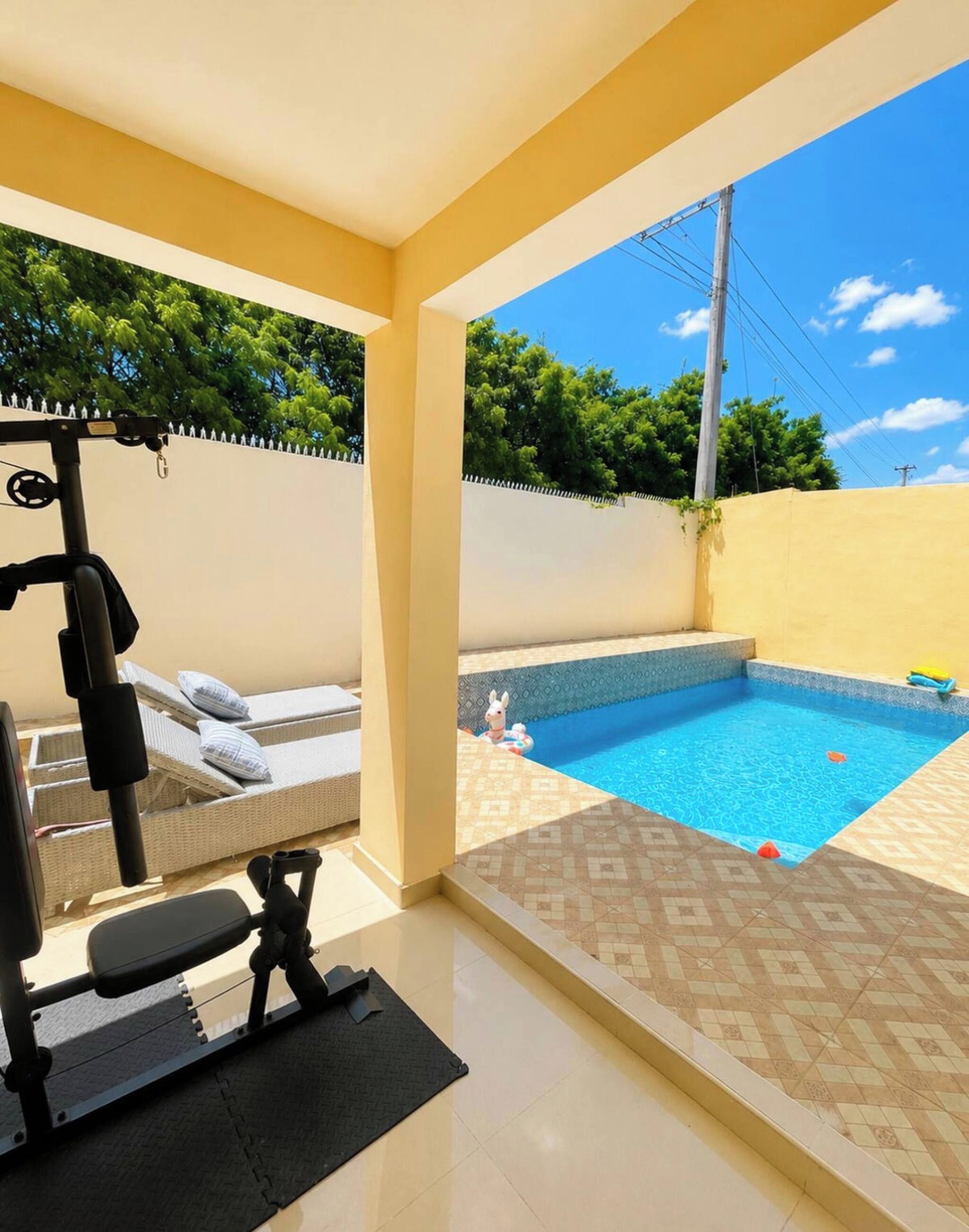 Ein Fitnessraum mit Trainingsgeräten und ein kleiner Pool mit Fliesen.