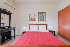 Ein Schlafzimmer mit einem Bett, zwei Nachttischen inklusive Lampen, einem Kleiderschrank und zwei gerahmten Bildern an der Wand.