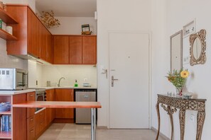 A compact kitchen with wooden cabinets, a microwave, a sink, and a dishwasher. - Apartment 'Cozy Home Near The Sea 12' with Balcony, Wi-Fi and Air Conditioning (Ρέθυμνο)