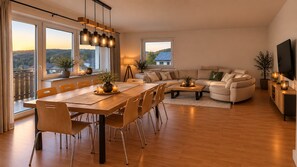 Ein modernes Wohnzimmer mit Essbereich, großen Fenstern und Blick ins Freie.