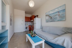 Um espaço compacto com cozinha compacta, sofá e uma pintura.