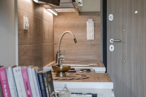 A modern kitchen with a wooden backsplash, a stainless steel sink, and a built-in oven. - Studio Apartment 'Cozy Home Near The Sea 13' with Balcony, Wi-Fi and Air Conditioning (Ρέθυμνο)