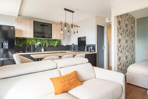 A modern living room with a sofa, a coffee table, and a decorative pillow. - L'Écrin des Aiguilles - Proche remontées mécanique (Fontcouverte-la-Toussuire)