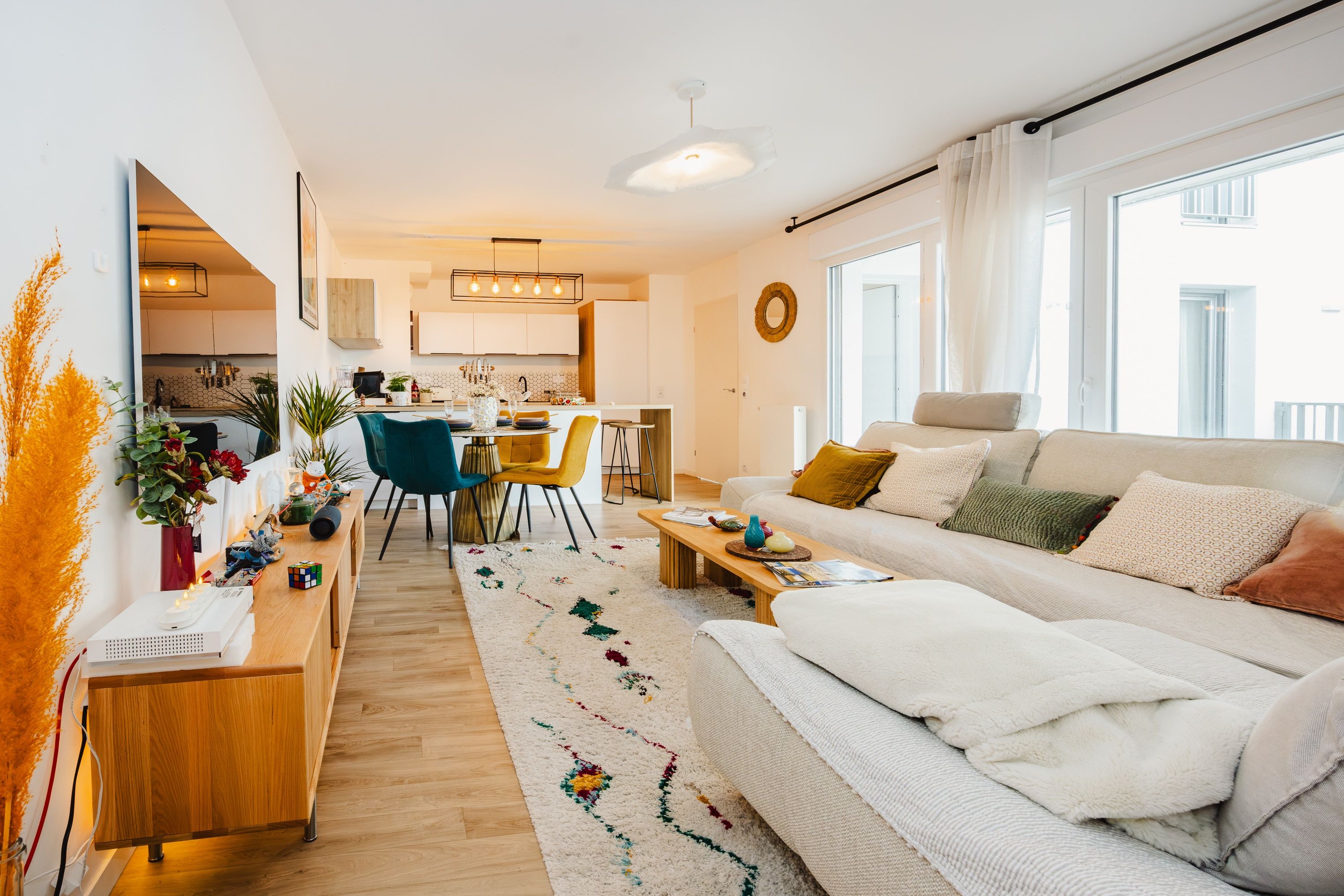 A modern living room with a sofa, coffee table, and a dining area with chairs and a kitchen in the background.