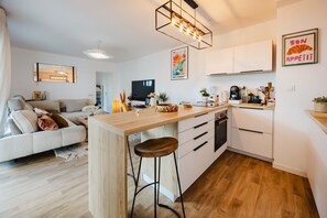 Eine moderne Küche mit einer Holzinsel, Barhocker und einem Essbereich mit einer Couch.
