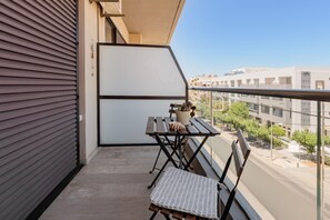 A balcony with a table and chairs, a potted plant, and a view of the cityscape. - Cozy Home Near The Sea 14 Studio with Sea View, Wi-Fi, and Air Conditioning (Ρέθυμνο)