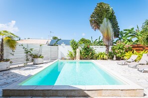 A rectangular swimming pool with a clear blue water surface, surrounded by a stone deck and various tropical plants. - Villa La Saline - Piscine Privée (Saint-Francois)
