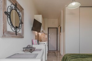Ein Flur mit einem an der Wand befestigten Flachbildfernseher, einem kleinen Tisch mit einem dekorativen Gegenstand und einer Tür am Ende.