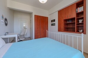 Une chambre à coucher comprenant un lit, un bureau, une chaise, une armoire et une bibliothèque.