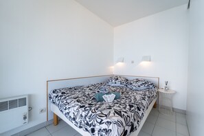 Een moderne slaapkamer met een bed, een nachtkastje en een wandlamp.