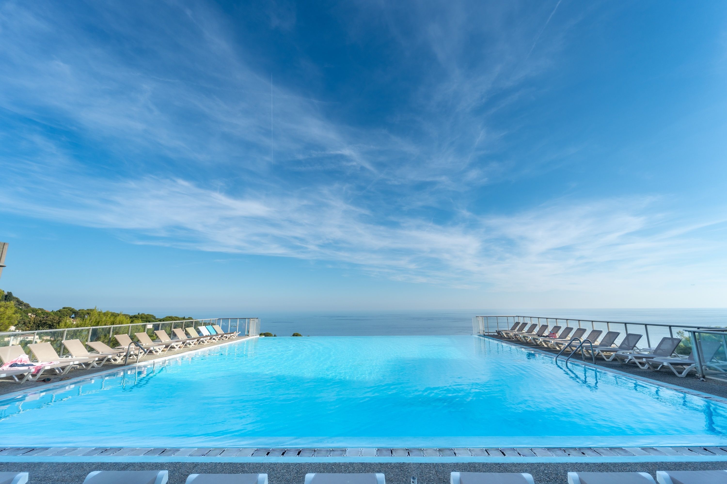 A clear blue sky with a pool and lounge chairs.