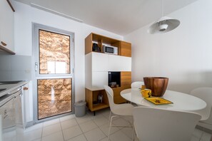 Een compacte keuken met een magnetron, een spoelbak en een eethoek met een tafel en stoelen.