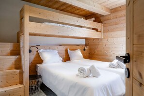 A wooden bunk bed with white bedding and towels, a small round table, and a black wall-mounted lamp. - Petit Chouda - Proche Télécabines (Saint-Chaffrey)