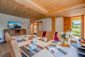 A dining area with a wooden ceiling, a television, and a view of the outdoors. - Petit Chouda - Proche Télécabines (Saint-Chaffrey)