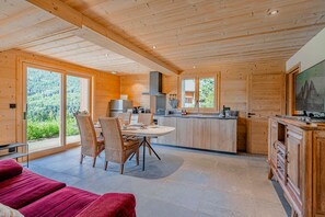 A modern kitchen with wooden cabinetry and a dining area with wicker chairs. - Petit Chouda - Proche Télécabines (Saint-Chaffrey)
