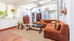 A living room with a sofa, armchair, and coffee table, a cabinet, and a lamp. - Marais Saint Paul Atypique (Paris)