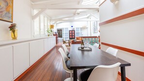 A dining area with a long table, chairs, and a view of the kitchen and living room. - Marais Saint Paul Atypique (Paris)
