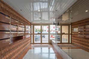 A lobby with a modern design, featuring a patterned wall, a reception desk, and a view of the street outside. - La Petite Pinède - Juan les pins (Antibes)