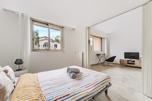 Une chambre à coucher avec un lit, une télévision, une chaise et une fenêtre.