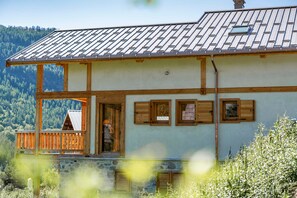 A two-story building with a balcony, wooden shutters, and a metal roof. - Grand Chouda - Vue Montagne (Saint-Chaffrey)