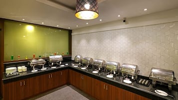 Una cocina de hotel con barra de buffet, varios dispensadores de alimentos y un espejo grande sobre la encimera.